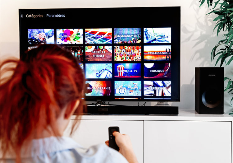 A woman using TV with external soundbar