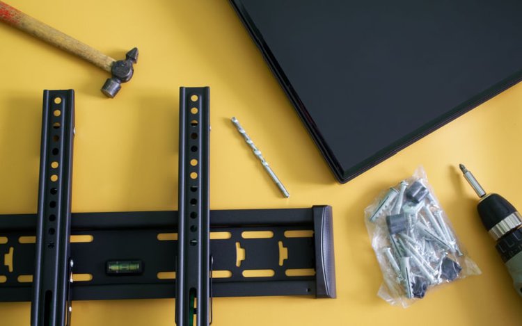 Bracket for TV wall mounting with screwdriver, hammer fasteners, and monitor screen