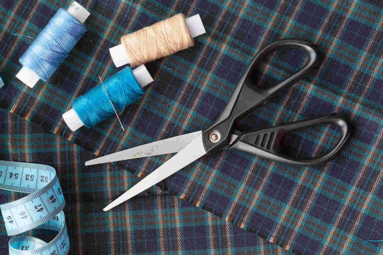 Plaid fabric, tailor scissors, threads close-up