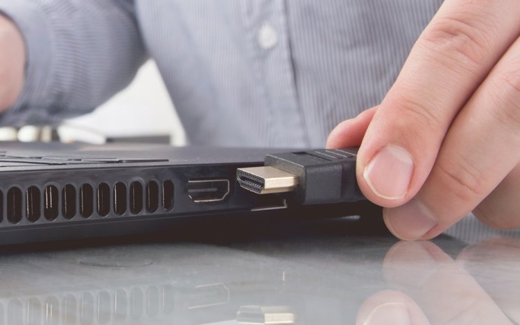 a man is going to plug an HDMI cable into his laptop