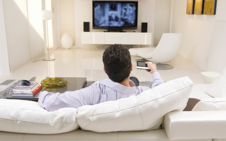 a man sits on a couch watching tv