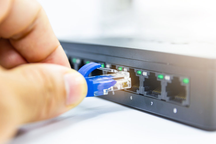 hand plugging a blue Ethernet cable to a router