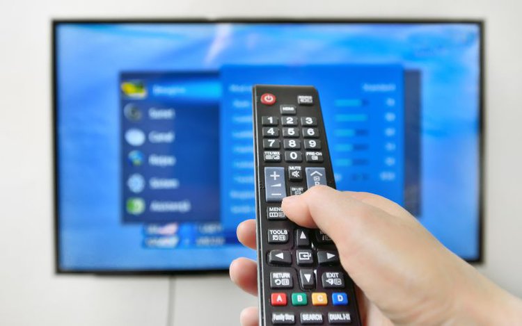 hand pressing the remote of a smart tv