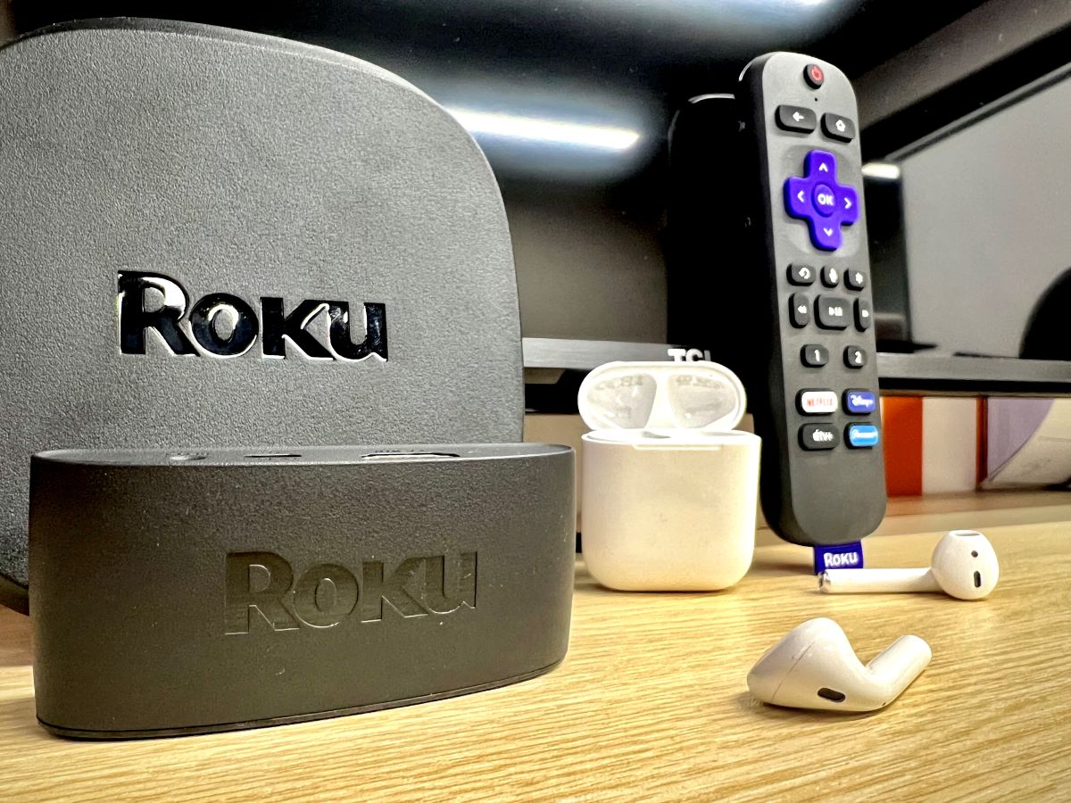 two roku players, a roku remote with a pair of airpods on a table in front of a tcl tv