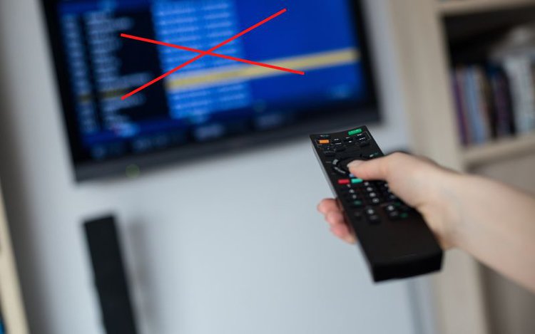 woman holding remote control towards TV screen with a red X on