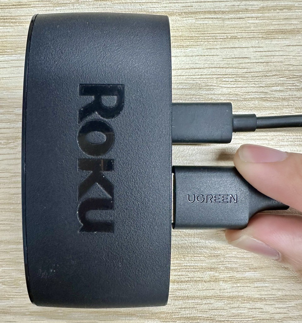a hand plugging an hdmi cable into a roku