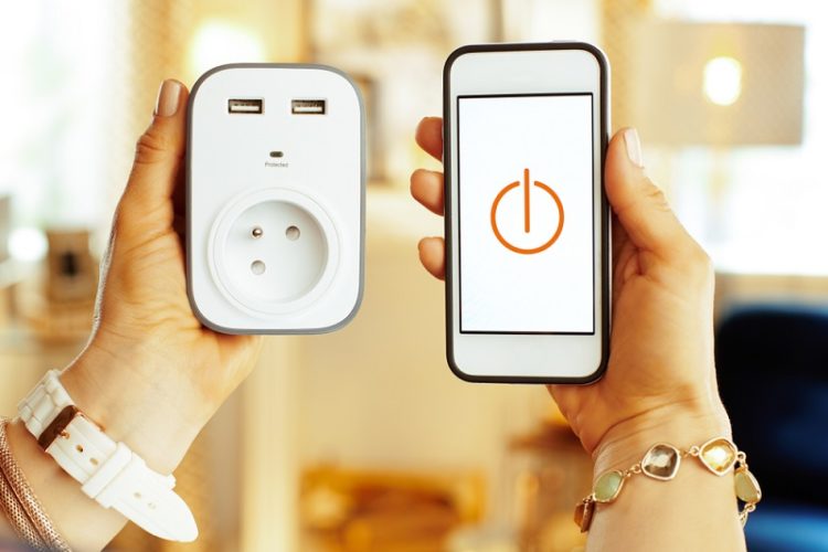 holding smart plug and a phone with smart plug app