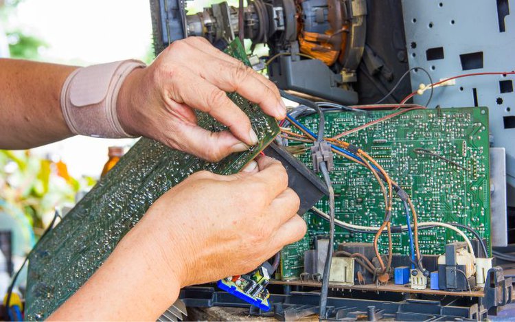 man fixing the circuit board of tv