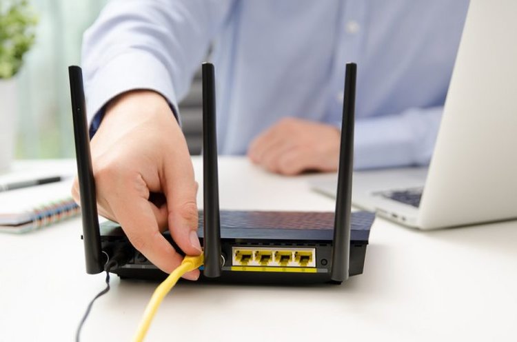 man plugging ethernet cable into router