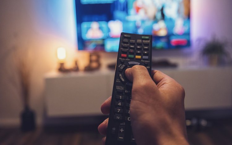man uses a remote to turn on a TV