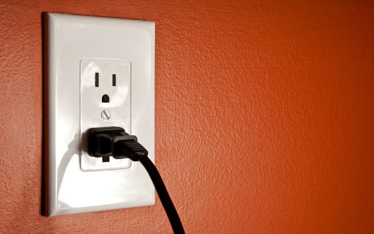 power cable in outlet on orange wall