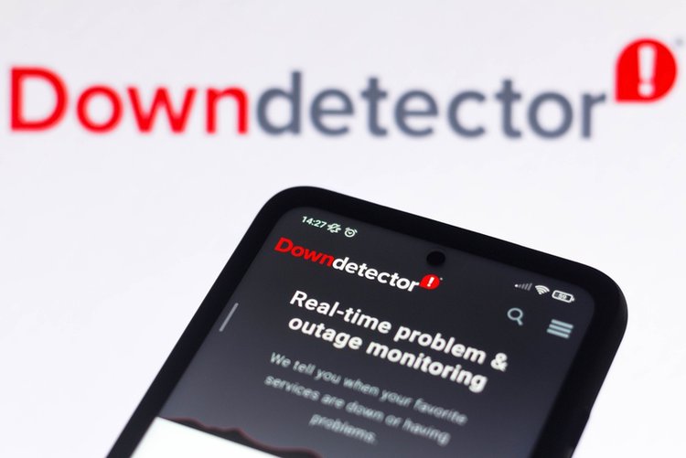 the Down Detector webpage on a smartphone and its logo in the background