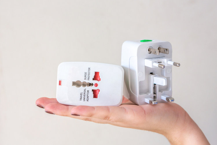woman's hand holding a white travel adapter