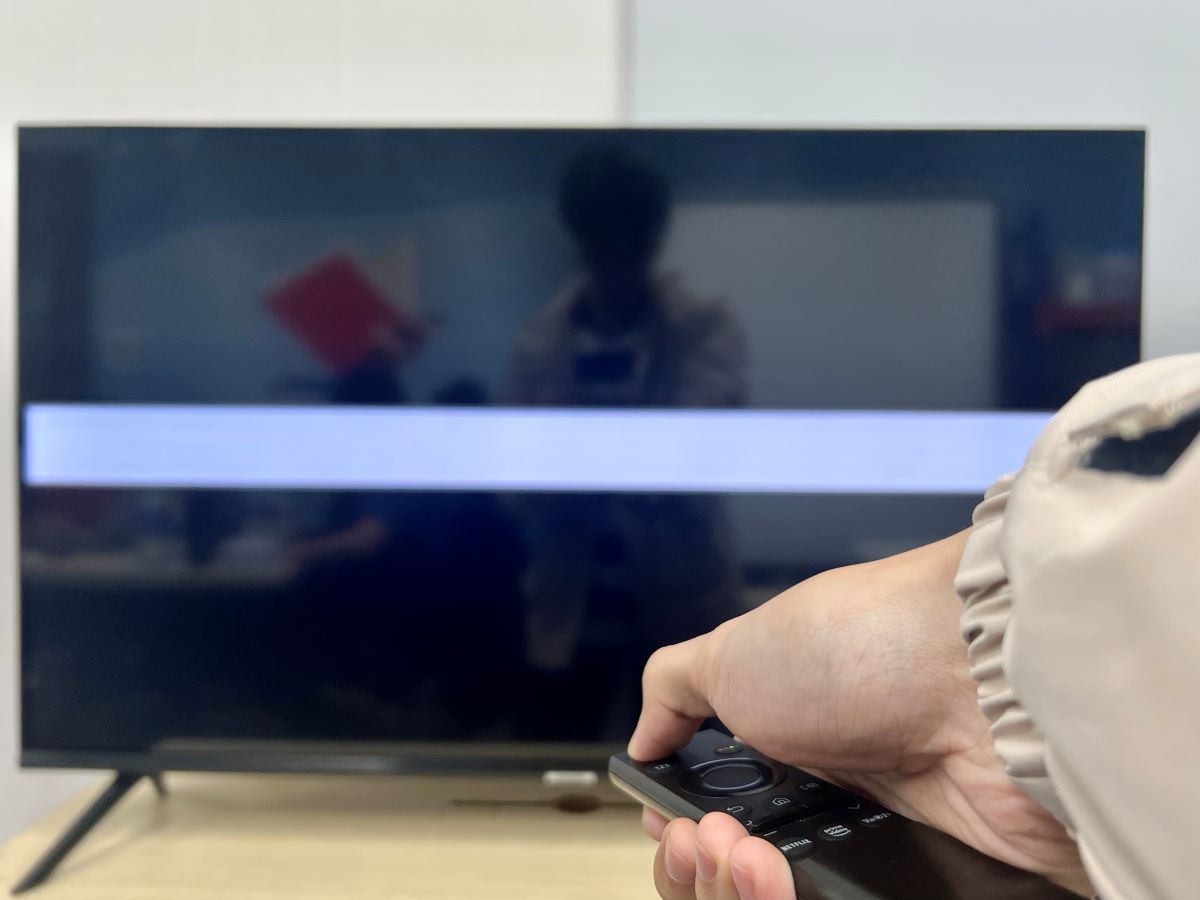 a hand holding a remote and turning off a samsung tv