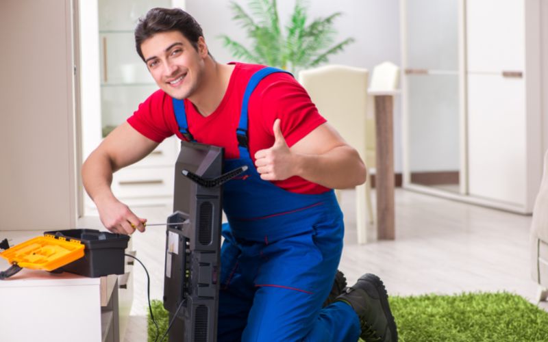 a smiling technician reparing the TV at home