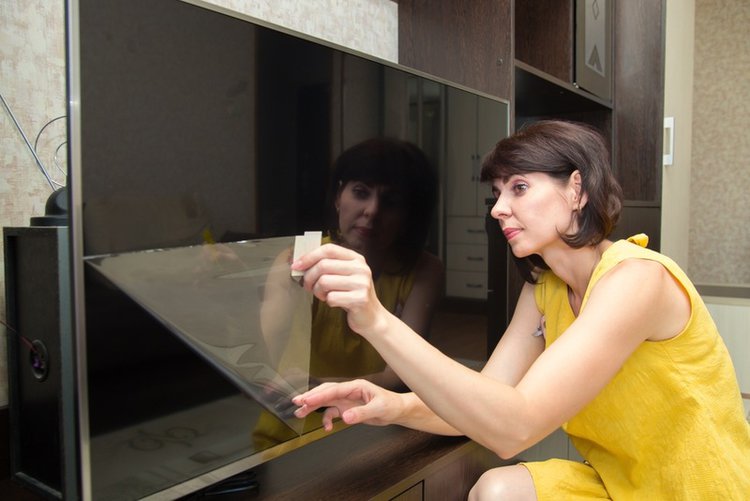 a woman in yellow dress removing the TV protective film