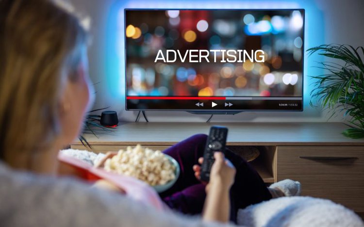 a woman watching TV with white advertising words on the TV screen