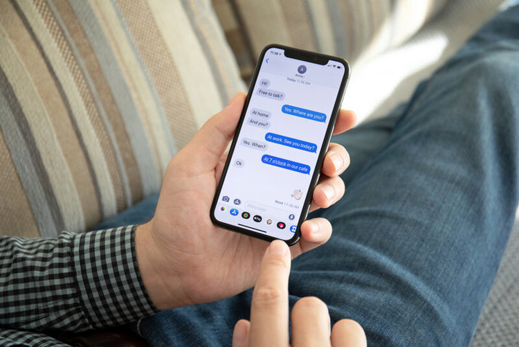 man laying on sofa using iMessage on an iPhone