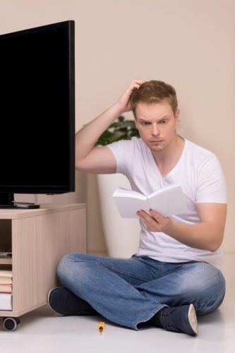 man reading TV user manual