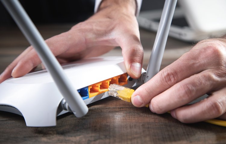 A man using ethernet cable to plug in wifi router