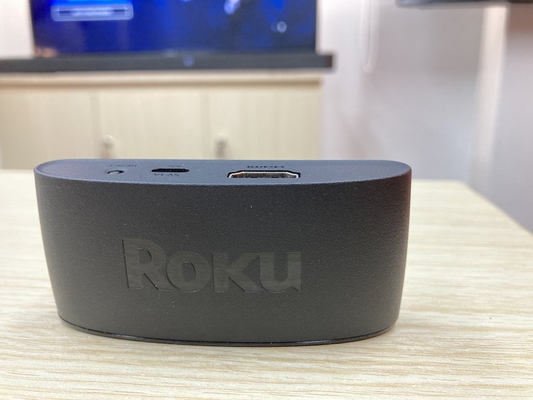 a Roku Express 4K on table with a TV behind