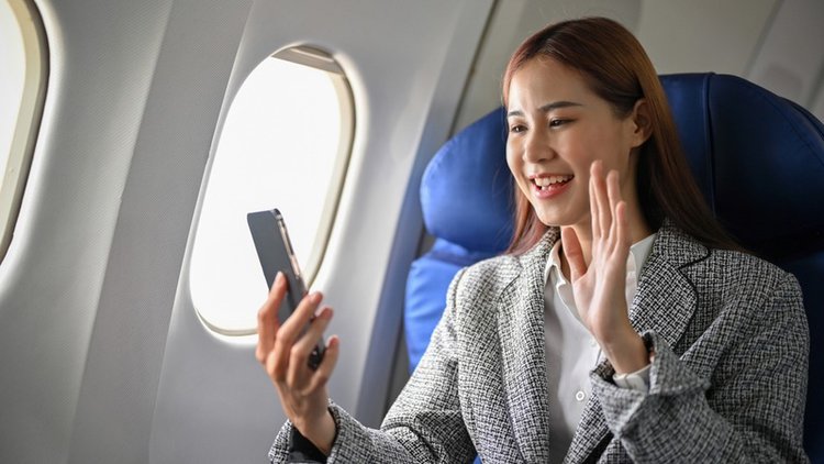 a cheerful business woman making a video call during flight