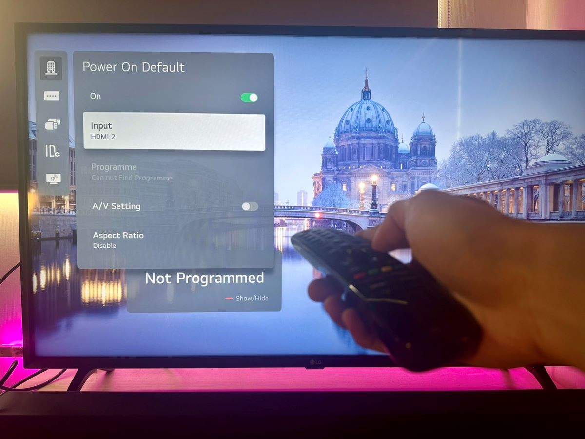 a hand holding an lg tv remote, power on default has been set up
