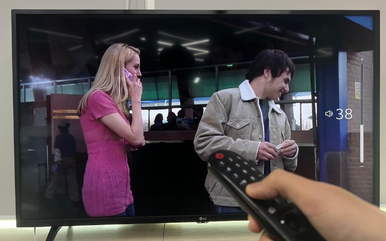 a man increases the TV volumne with the remote