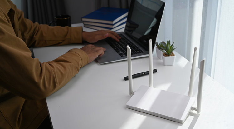 a man working on his laptop next to a white router