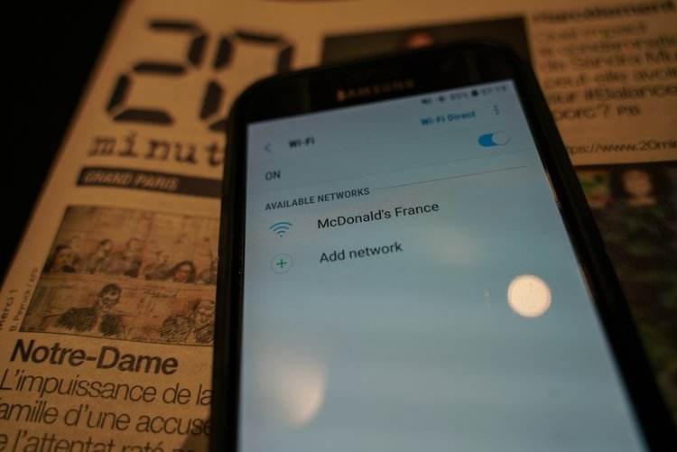 a phone showing a free wifi McDonald France signal and a newspaper in background