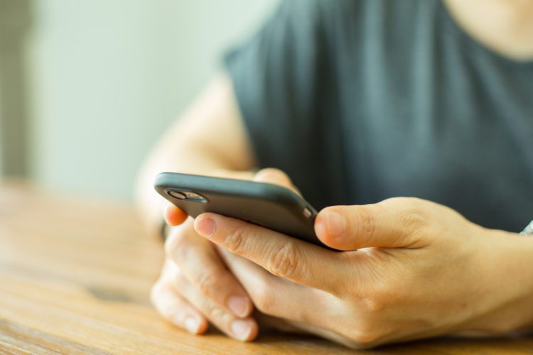 a woman holding a smartphone on her hands which is laying on the table