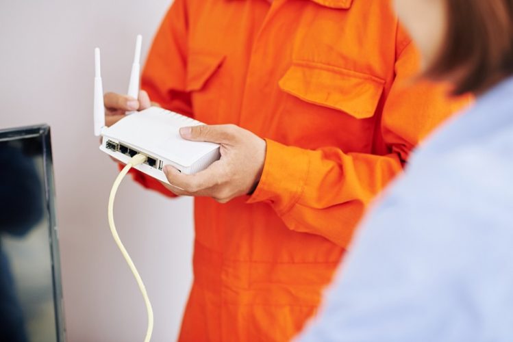 an electrician man holding wifi router on his hands
