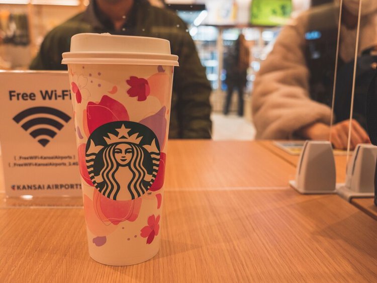 close-up view of cup of Starbucks coffee with free Wifi sign behind