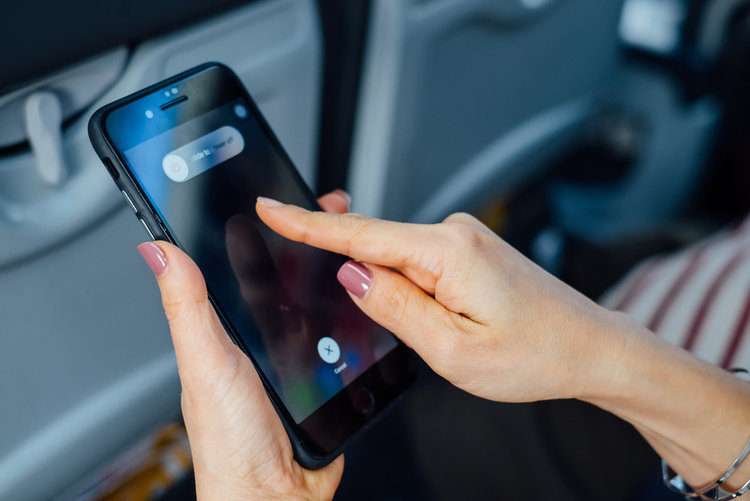 hand holding iPhone with slide to turn off during flight