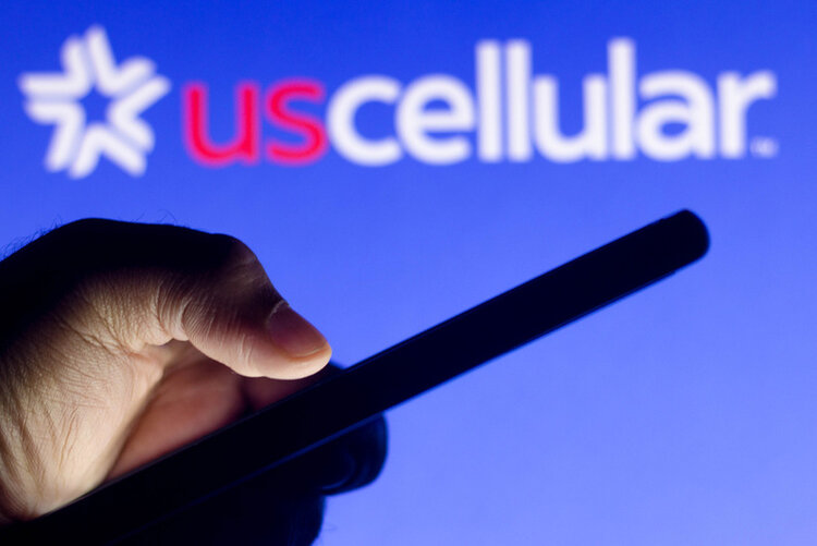 hand holding a phone in front of the US Cellular logo in the background