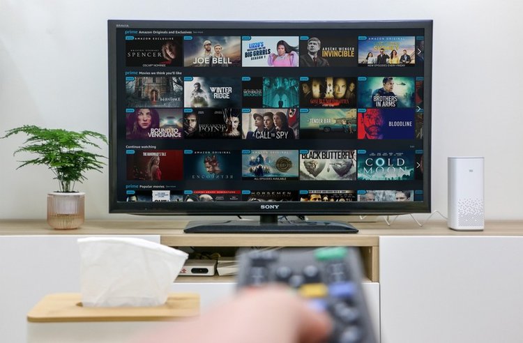 hand holding remote towards Sony TV with Amazon Prime app on