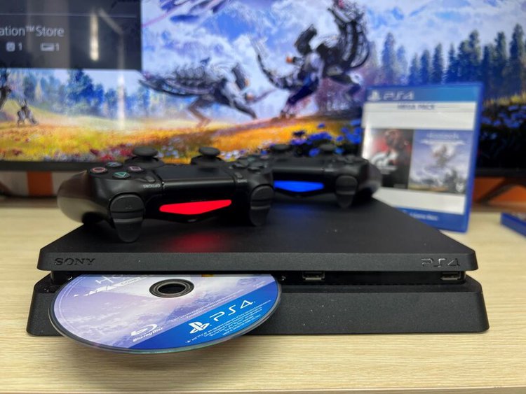 Horizon Zero Dawn game disc inside the PS4 with the box and controllers