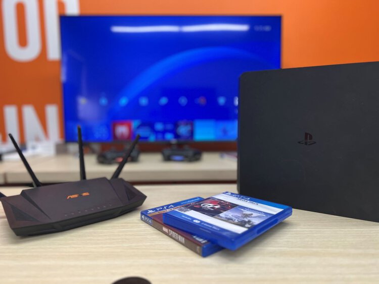 Asus router with PS4 and PS4 disc games on a table