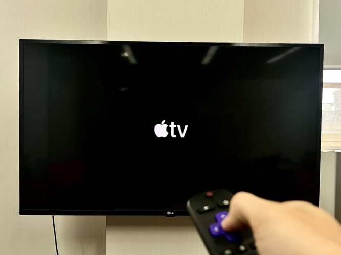 apple tv icon on an lg tv, a hand holding roku remote