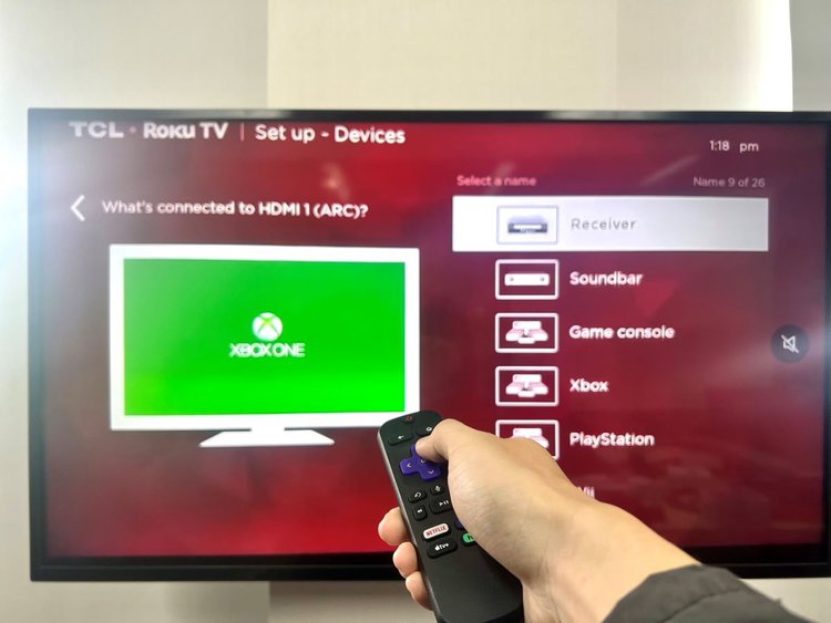 a man holding a roku remote and pointing at a tv