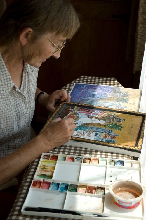 a old lady is painting in her room