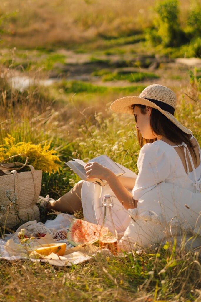 a woman in white is reading book outdoors