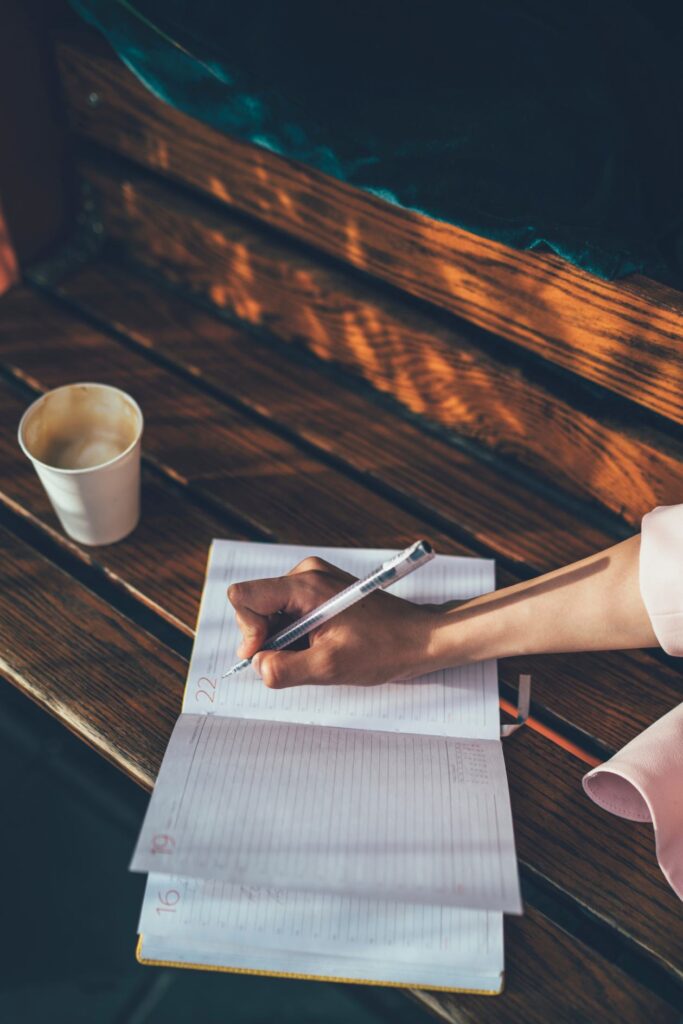 a woman is writing on notebook