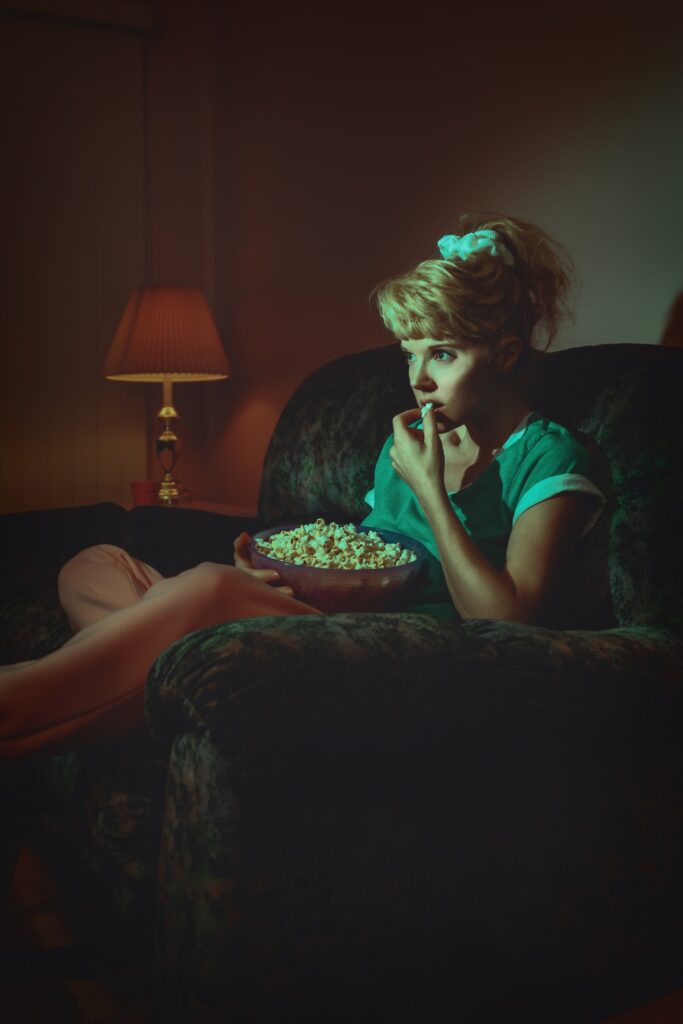 girl is eating pop corn and watching tv