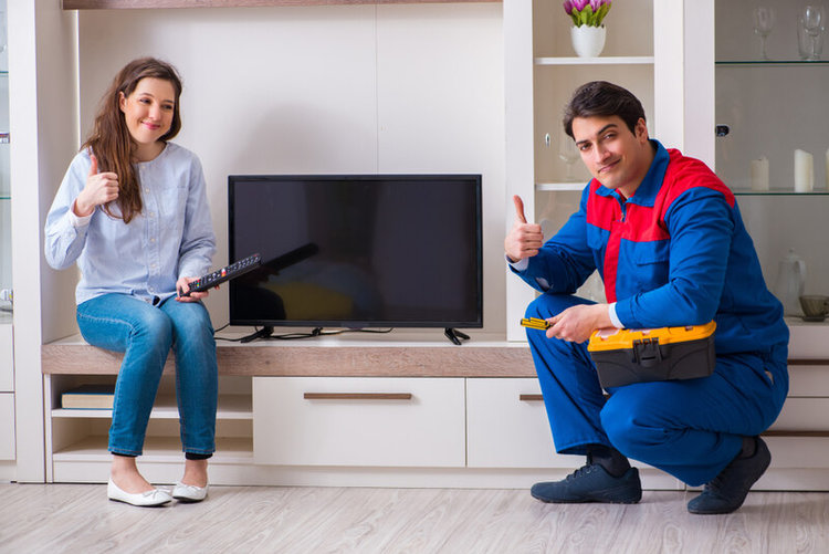 happy young female and male TV technician in the living room