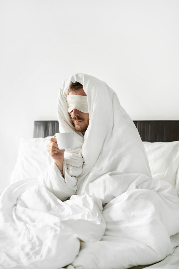 man is in bed, and is drinking coffee