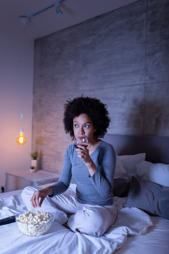 woman is watching TV and eating popcorn