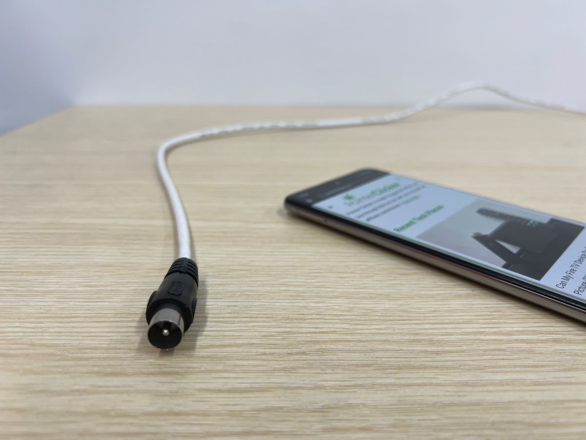 A coaxial cable with a Samsung smart phone on a wooden table
