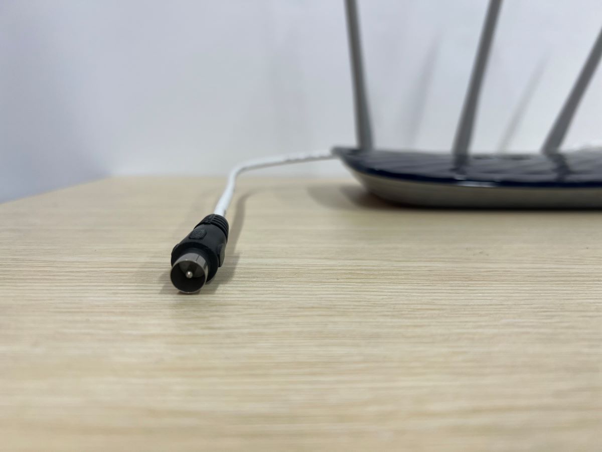 A coaxial cable with the TP-Link router on a wooden table