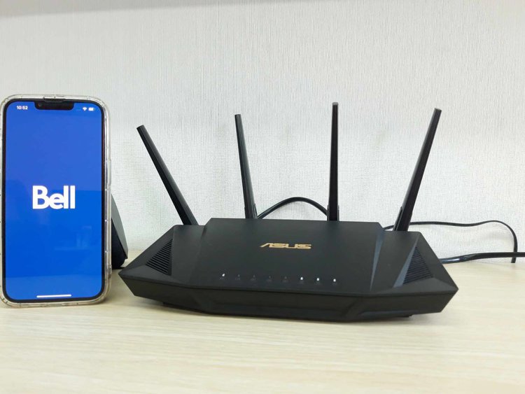 Bell on iPhone 13 with Asus router on a wooden table
